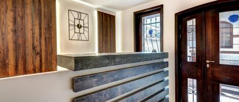 Un área de recepción moderna con un panel de madera, una obra de arte geométrica y un mostrador de recepción de tonos oscuros.