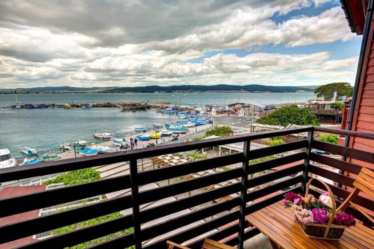A balcony with a view of a harbor, boats, and a distant shoreline.