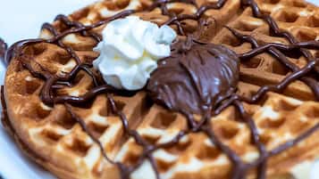 A waffle with chocolate syrup and whipped cream on a plate.
