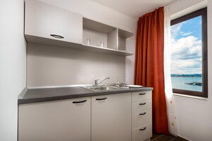Cocina moderna con armarios blancos, encimera gris y ventana con vista al agua y tierra distante.
