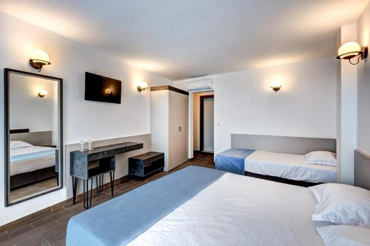 A hotel room with two beds, a desk, and a mirror.