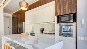 Une cuisine moderne dotée d’un plan de travail en marbre, d’appareils électroménagers en acier inoxydable et d’éléments décoratifs en bois.