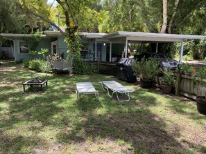 Enjoy a shaded outdoor space with a patio, lounge chairs, and a small table, perfect for casual gatherings and outdoor cooking.
