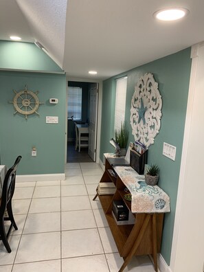 Stylish hallway leads to a dining area with a wooden table and potted plant.