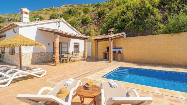 Un área junto a la piscina con sillones, una mesa y una piscina pequeña.