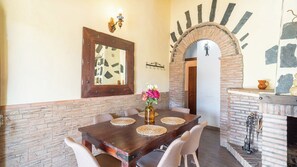 A dining area with a wooden table, woven placemats, and a vase of flowers.