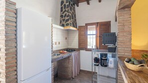 Una cocina con refrigerador, estufa, lavaplatos y cafetera.