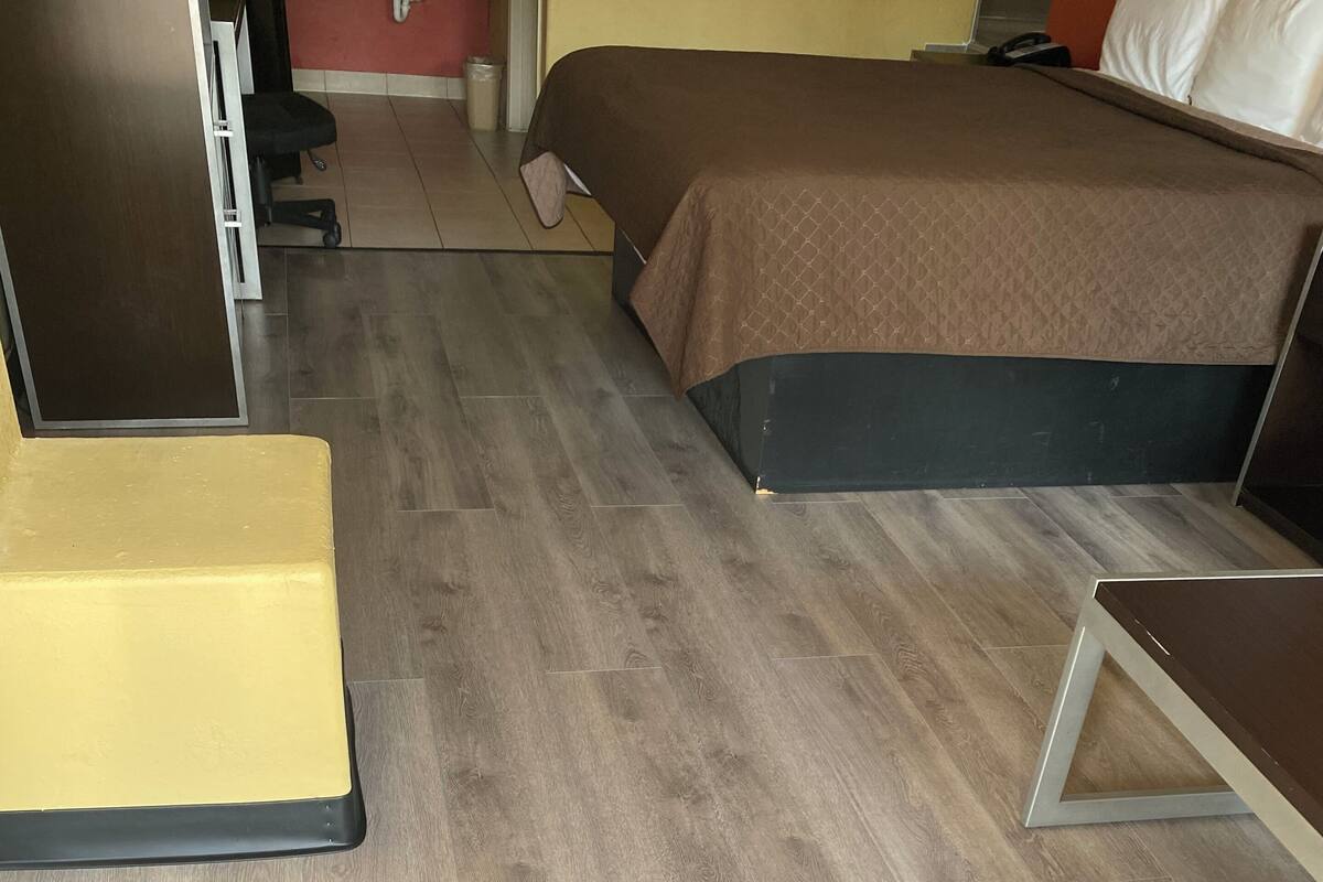 A hotel room with a bed, a desk, a chair, and a small table.