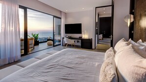 A modern bedroom with a large bed, a desk, and a TV. It has a balcony with a view of the ocean. - Sail View Ocean Views, Rooftop Pool, Romantic Zone (Puerto Vallarta)