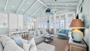 A spacious living room with a high ceiling, large windows, and a view of the outdoors.