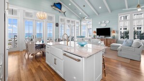 A spacious kitchen with a large island, white cabinetry, and a view of the ocean.