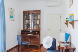 A room with a wooden cabinet, a blue chair, a white door, and a shelf with a book and a plant.