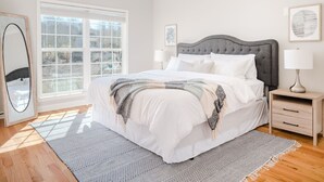 Un dormitorio con una cama grande, una mesita de noche, un espejo y una ventana con persianas.