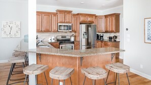 Una cocina moderna con armarios de madera, electrodomésticos de acero inoxidable y una isla central con taburetes de bar.