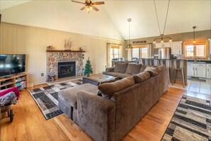 Relax in this inviting living area with a stone fireplace, comfortable sectional sofa, and modern kitchen.