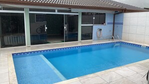 Ein Schwimmbad mit gefliestem Deck, Glasfenstern und einer Wand aus Fliesen.