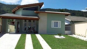 Ein zweistöckiges Haus mit Ziegeldach, einer überdachten Veranda und einem gepflegten Rasen.