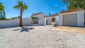 Une propriété située sur la côte, avec une allée en gravier, un palmier et un bâtiment blanc doté d’un toit en tuiles.
