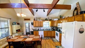 Una cocina con armarios de madera, un refrigerador blanco y un comedor con una mesa y sillas de madera.