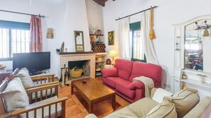Ein gemütliches Wohnzimmer mit Kamin, einem roten Sofa, einem Holztisch und einem Fernseher.