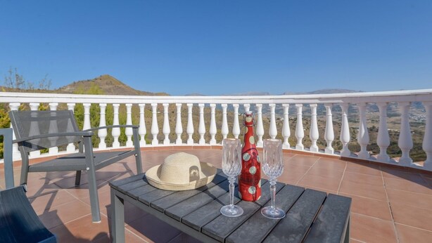 Eine Terrasse mit Tisch für zwei Personen, einer Flasche und einem Hut.