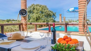 A table set with a wine bottle, glasses, a hat, a basket of oranges, and a laptop with a book. - Casa Rural Bellavista Ronda by Ruralidays (Málaga)
