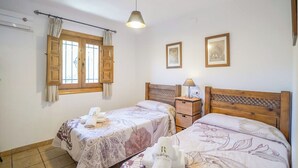A bedroom with two single beds, a wooden headboard, a nightstand with a lamp, and a window with curtains. - Cortijo los Chinos Órgiva by Ruralidays (Granada)