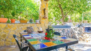 An outdoor patio with a stone wall, a tiled table, and potted plants. - Cortijo los Chinos Órgiva by Ruralidays (Granada)