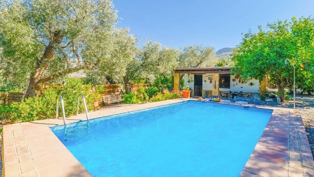 A rectangular swimming pool with a wooden deck and a small structure with a door and windows. - Cortijo los Chinos Órgiva by Ruralidays (Granada)