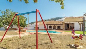 Un barrio residencial con un columpio, una piscina y una casa de techo de tejas.