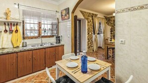 Una cocina compacta con armarios de madera, un lavamanos y una mesa de comedor preparada para cuatro comensales.