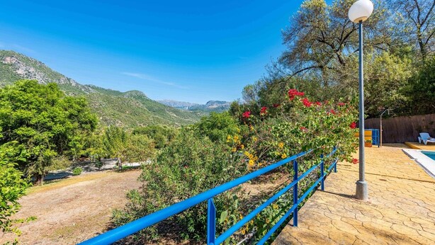 A poolside area with a blue railing, a lamp post, and a view of a mountainous landscape. - Casa La Fresneda Ubrique by Ruralidays (Cádiz)