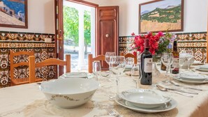 A dining table set for six with a bottle of wine, glasses, and plates. - Casa La Fresneda Ubrique by Ruralidays (Cádiz)