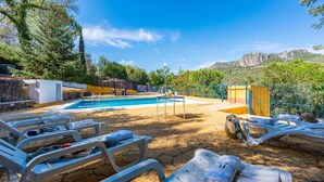 A pool area with lounge chairs, a table, and a view of the surrounding landscape. - Casa La Fresneda Ubrique by Ruralidays (Cádiz)