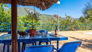 An outdoor dining area with a table set for two, a potted plant, and a bottle of wine. - Casa La Fresneda Ubrique by Ruralidays (Cádiz)