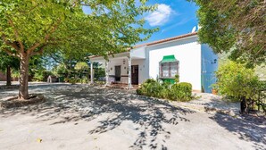 A white building with a green awning, a covered patio, and a small garden area. - Casa La Fresneda Ubrique by Ruralidays (Cádiz)