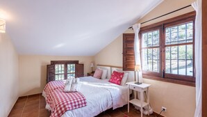 Camera da letto con un letto, due comodini, una finestra con tende e vista sul verde.