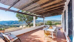 An outdoor patio with a table and chairs, a pergola, and a view of the countryside. - Marrucho Alto Riogordo by Ruralidays (Málaga)