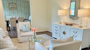 A living room with a white sofa, a glass coffee table, and a white dresser with lamps. - Prime Location Masters Rental - Only 2.2 miles from course in Augusta, GA! (Augusta)