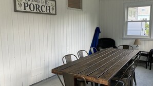 Ein langer Holztisch mit Metallstühlen in einem Raum mit weiß gefasten Wänden und einer Deckenleuchte.