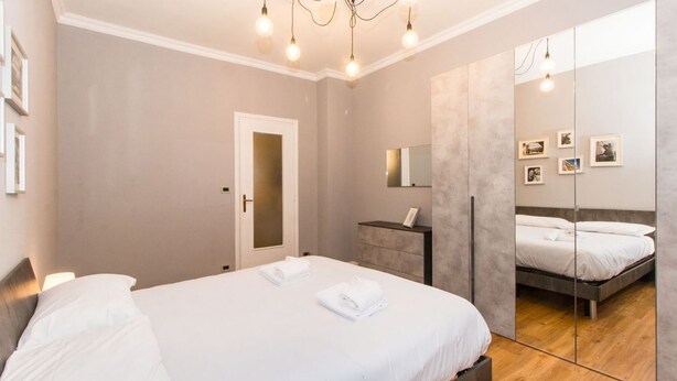A modern bedroom with a large bed, a bedside table, a mirror, and a door. - GuestHost - Very new apartment equipped with large terrace and totally renovated, able to comfortably accommodate up to 3 people. The flat is located in the quiet Parella district, a very green and well served area: the MM Pozzo Strada stop is only 400m  (Torino)
