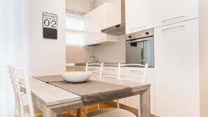 A modern kitchen with white cabinets, a built-in oven, and a dining area with a table and chairs. - GuestHost - Very new apartment equipped with large terrace and totally renovated, able to comfortably accommodate up to 3 people. The flat is located in the quiet Parella district, a very green and well served area: the MM Pozzo Strada stop is only 400m  (Torino)