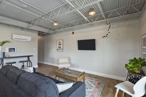 Una sala de estar moderna con un sofá, una mesa de centro y un televisor montado en la pared.