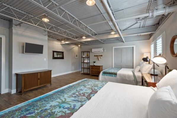 A hotel room with a large bed, a desk, a chair, a television, and a window.