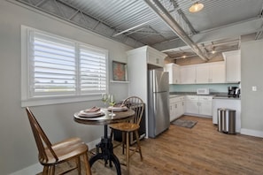 Una cocina moderna con armarios blancos, electrodomésticos de acero inoxidable y un comedor con una mesa redonda y sillas.