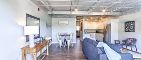 Un interior moderno con una zona de comedor, un sofá y una cocina al fondo.