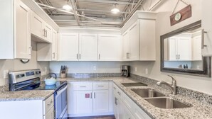 A kitchen with white cabinets, granite countertops, stainless steel appliances, and a large mirror above the sink.