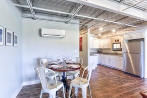 A dining area with a round table set for four, white chairs, and a kitchen in the background.