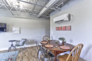 A dining area with a wooden table, metal chairs, and a ceiling with exposed beams.