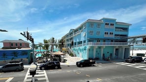 A multi-story hotel with balconies, a pool area, and a street view with cars and traffic lights.